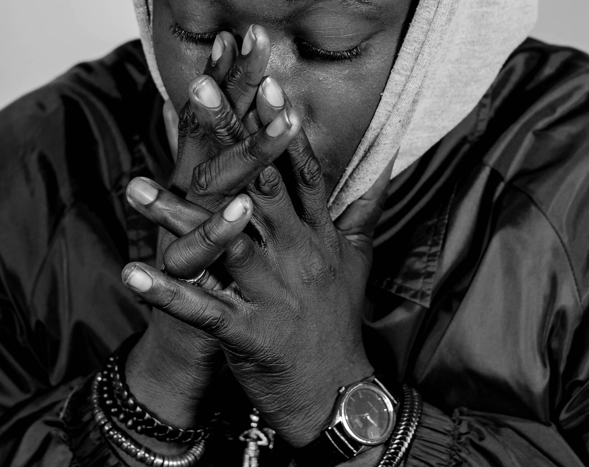 Do You Pray For Me? - Black and white intimate portrait of person in prayer with hands clasped, eyes closed in contemplation