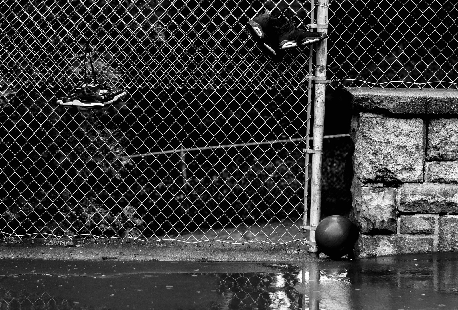 Hoop Dreams Deferred - Basketball on wet pavement next to chain-link fence in Providence, RI