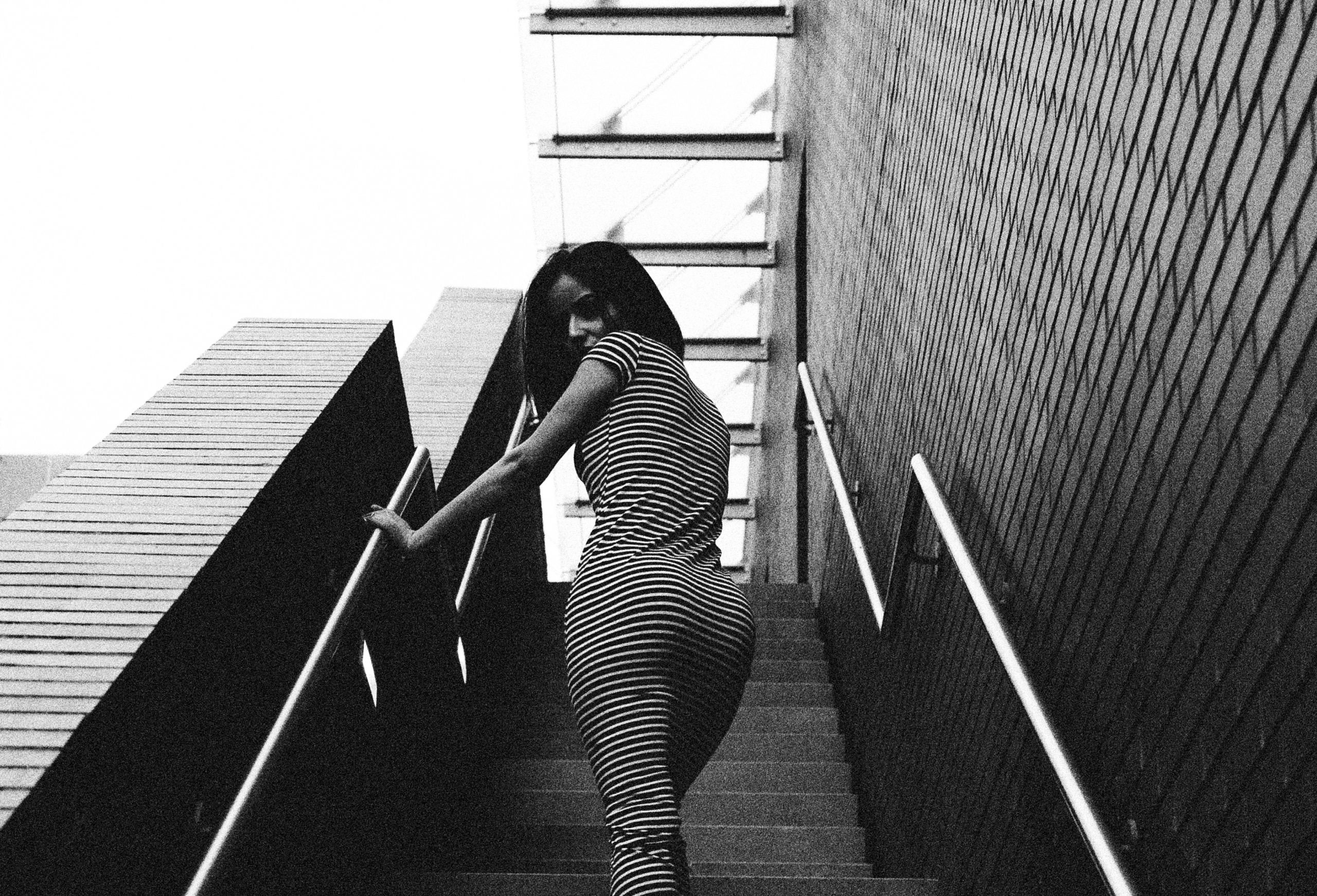 Maria Isabella - Black and white photograph of woman in striped dress walking up stairs in Boston