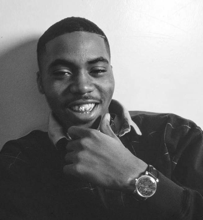 Black and white photograph of young Nas pointing at camera with a bright smile, wearing a collared shirt and watch